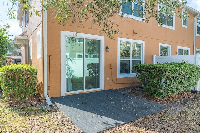 property entrance featuring a wooden deck and stucco siding