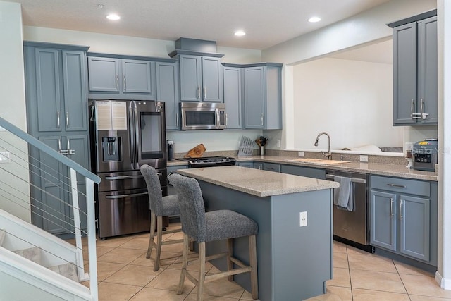 kitchen with a breakfast bar area, stainless steel appliances, light tile patterned flooring, a sink, and a kitchen island