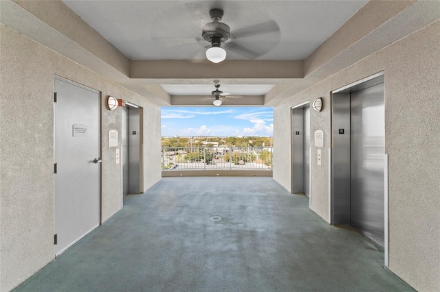 corridor with a textured wall, carpet flooring, and elevator