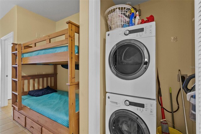 clothes washing area featuring laundry area, stacked washer / drying machine, and light tile patterned flooring