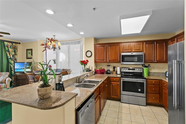 kitchen featuring a breakfast bar area, appliances with stainless steel finishes, light tile patterned flooring, a sink, and a peninsula