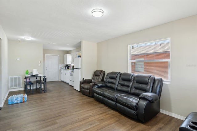 living area featuring visible vents, baseboards, and wood finished floors