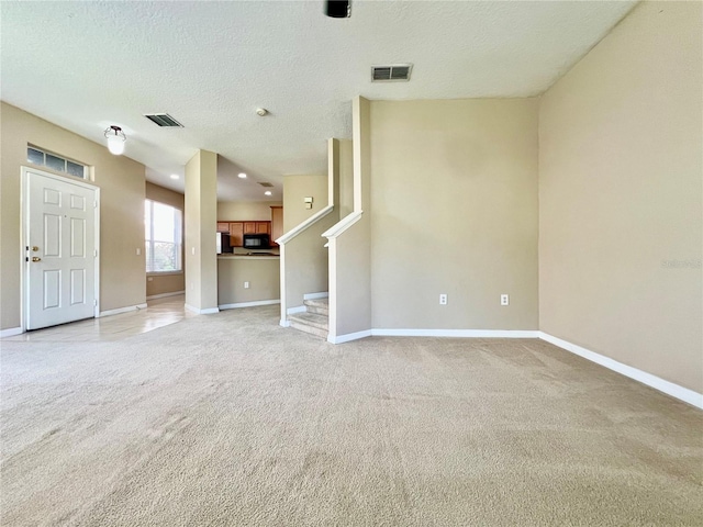 6640 S Goldenrod Rd Unit 118B, Orlando, FL 32822 - unfurnished living room with light colored carpet, baseboards, a textured ceiling, and stairway