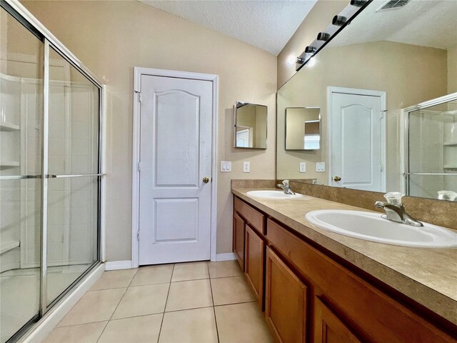 6640 S Goldenrod Rd Unit 118B, Orlando, FL 32822 - bathroom with tile patterned floors, double vanity, a stall shower, a textured ceiling, and vaulted ceiling