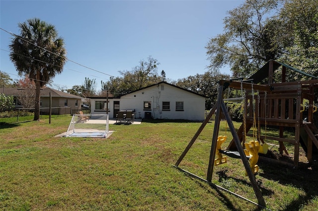 back of house with a playground, a lawn, and a patio area