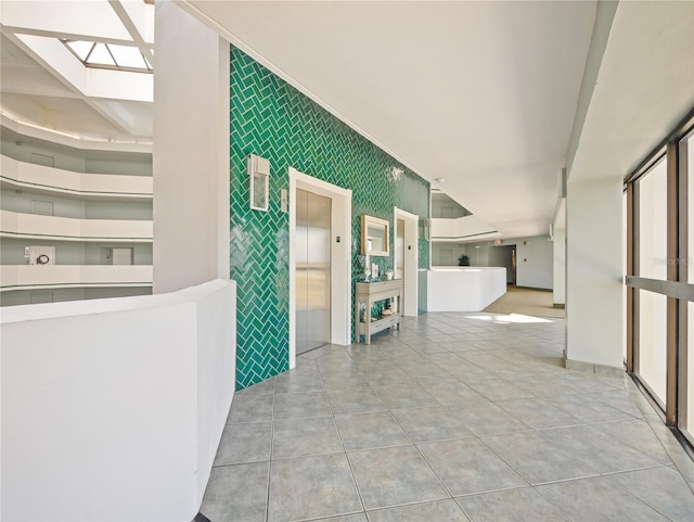 hallway featuring elevator, a skylight, and light tile patterned floors