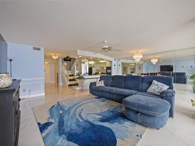 living room with ceiling fan with notable chandelier and a textured ceiling