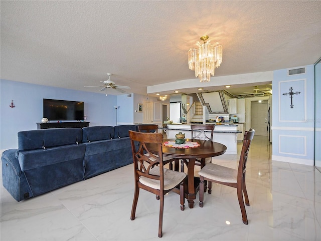 dining room with a textured ceiling and ceiling fan with notable chandelier