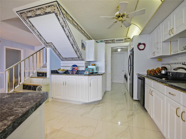 kitchen with a textured ceiling, stacked washing maching and dryer, white cabinets, and black appliances