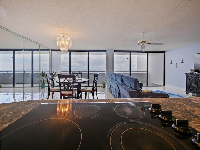 interior space featuring a wall of windows, ceiling fan with notable chandelier, and a textured ceiling