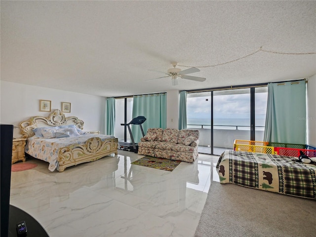 bedroom with a wall of windows, a water view, access to outside, and a textured ceiling