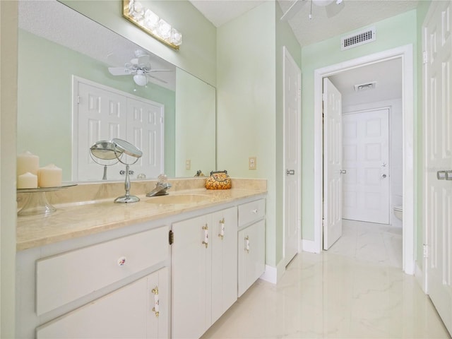 bathroom with toilet, vanity, and ceiling fan