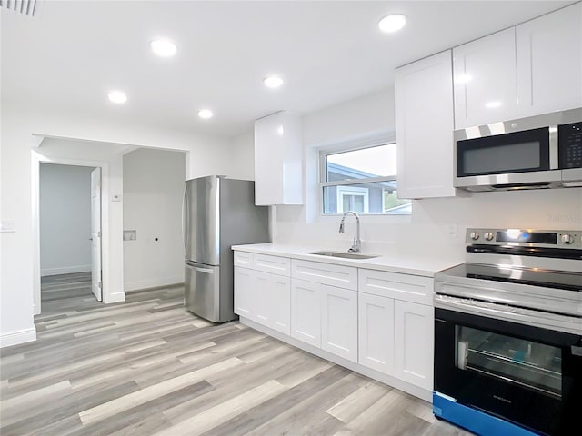 kitchen featuring sink, stainless steel appliances, white cabinets, and light hardwood / wood-style floors