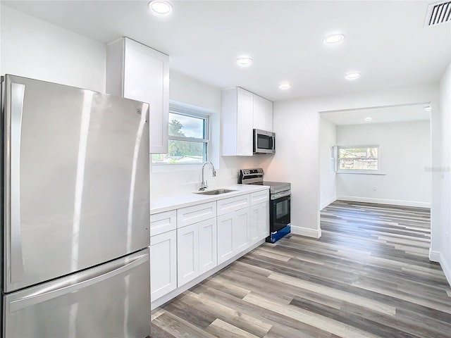 4502 Florence St, Apopka, FL 32712 - kitchen with sink, stainless steel appliances, white cabinetry, and light hardwood / wood-style floors