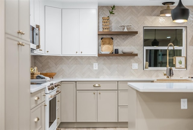 kitchen with high end range, sink, tasteful backsplash, and white cabinetry