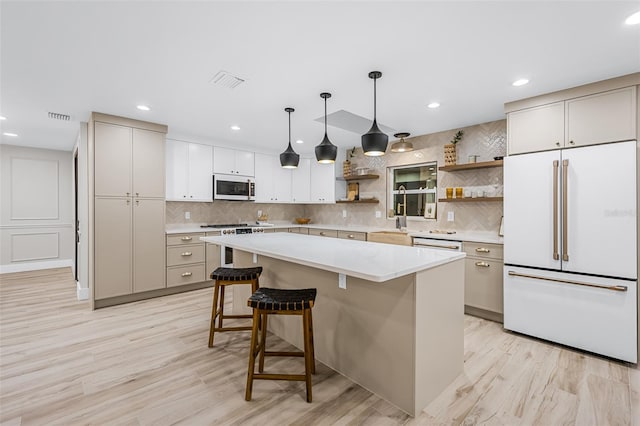 kitchen with white appliances, backsplash, a kitchen island, decorative light fixtures, and white cabinets