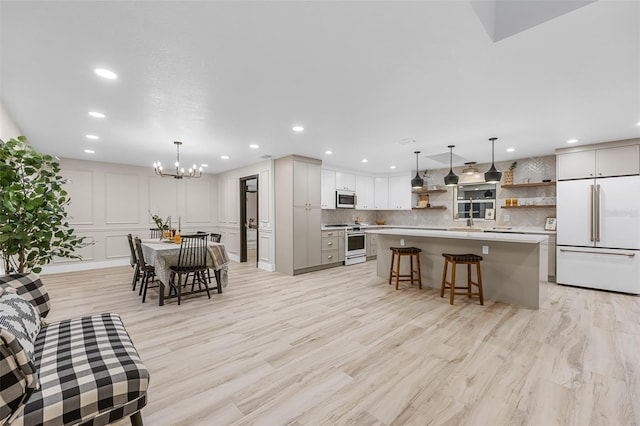 kitchen with high end appliances, a kitchen breakfast bar, a kitchen island, hanging light fixtures, and decorative backsplash