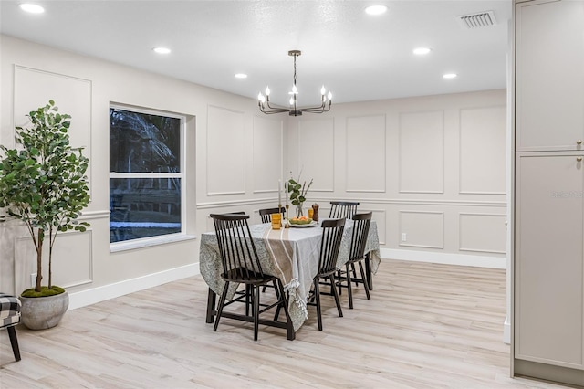 dining area with light wood-type flooring and a notable chandelier