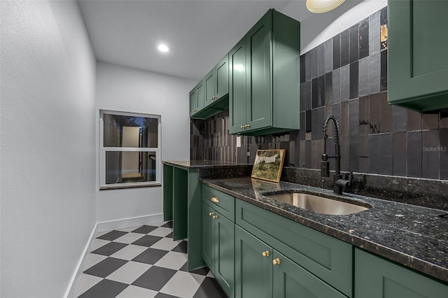 kitchen with decorative backsplash, sink, dark stone counters, and green cabinets