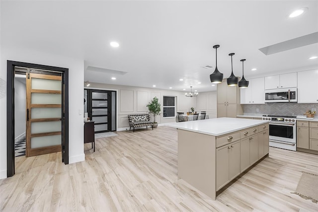 kitchen with backsplash, a notable chandelier, a kitchen island, decorative light fixtures, and range