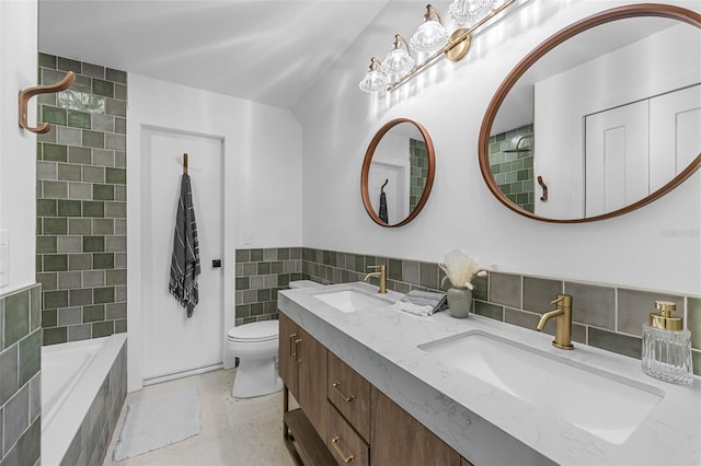 bathroom featuring tile walls, vanity, a washtub, and toilet