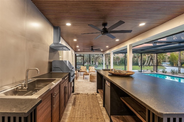 view of patio with glass enclosure, ceiling fan, an outdoor kitchen, area for grilling, and sink