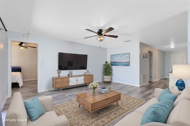 living room with light hardwood / wood-style flooring and ceiling fan