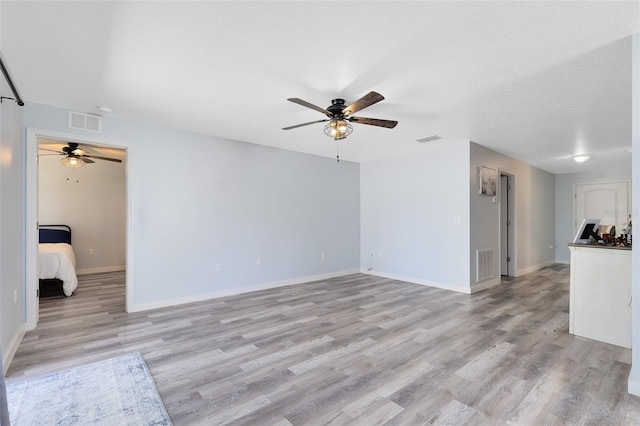 unfurnished living room with ceiling fan, light hardwood / wood-style flooring, and a textured ceiling