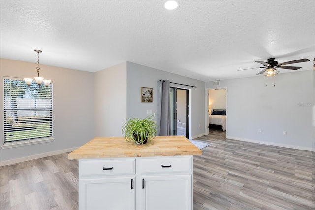 kitchen with light hardwood / wood-style flooring, butcher block counters, a center island, decorative light fixtures, and white cabinets