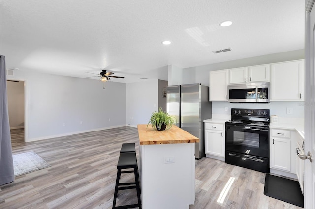 kitchen with wood counters, a breakfast bar area, appliances with stainless steel finishes, and white cabinets