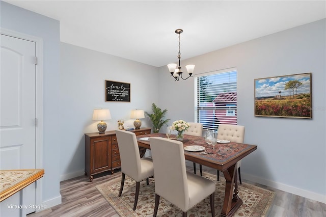 dining space featuring light hardwood / wood-style floors and an inviting chandelier