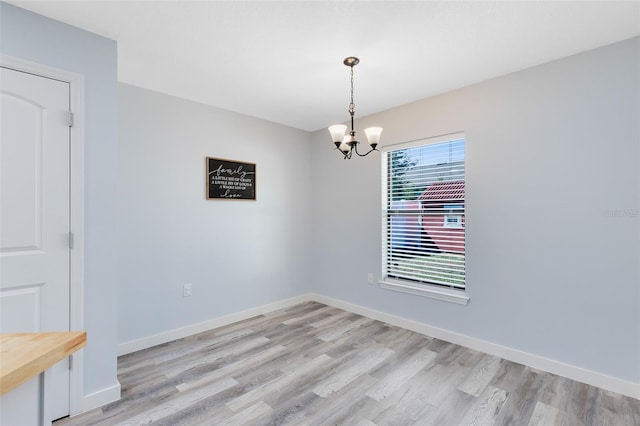 empty room featuring light wood-type flooring and an inviting chandelier