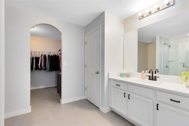 bathroom featuring a shower, vanity, a textured ceiling, and tile patterned flooring