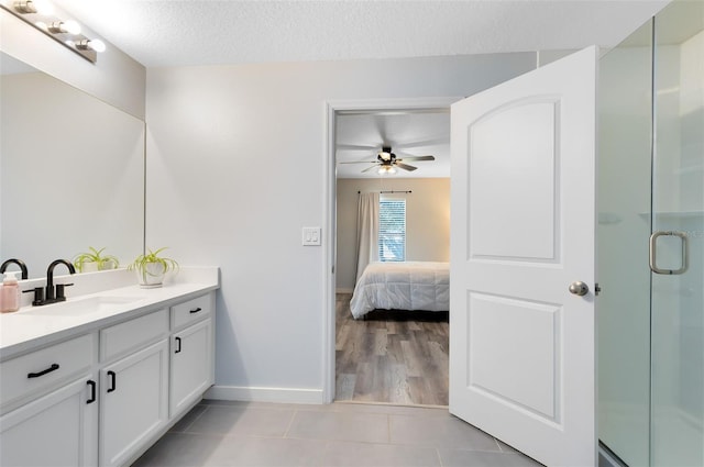 bathroom featuring a shower with door, a textured ceiling, ceiling fan, tile patterned floors, and vanity