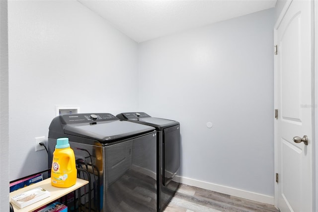 laundry area with hardwood / wood-style flooring and washing machine and clothes dryer