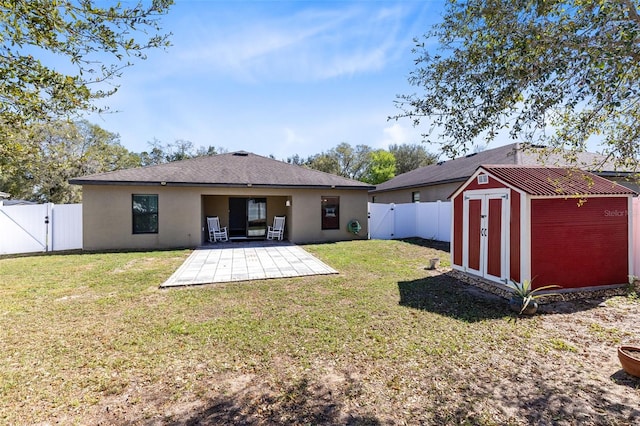 rear view of property with a patio, a yard, and a storage unit