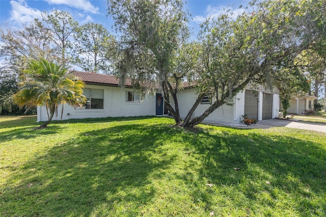 ranch-style home with concrete driveway, a tile roof, a front lawn, and stucco siding