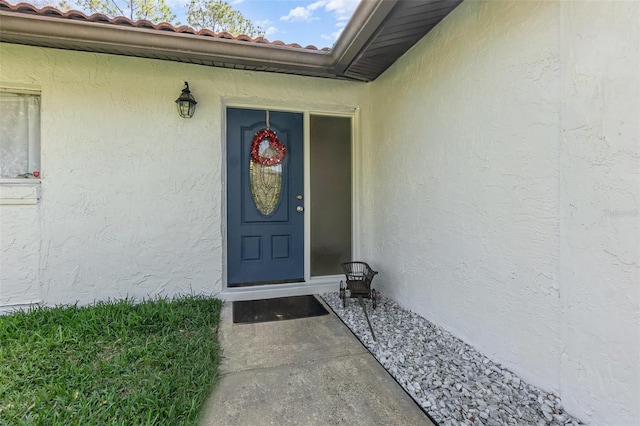 entrance to property with a tiled roof and stucco siding