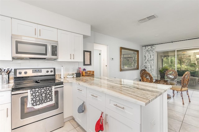 kitchen with visible vents, appliances with stainless steel finishes, white cabinets, light tile patterned flooring, and a peninsula