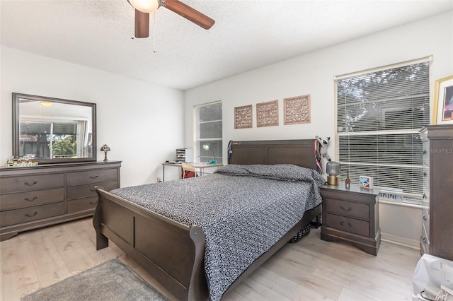 bedroom featuring light wood-style flooring, ceiling fan, and a textured ceiling