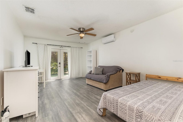 bedroom with wood finished floors, visible vents, access to exterior, french doors, and a wall mounted air conditioner