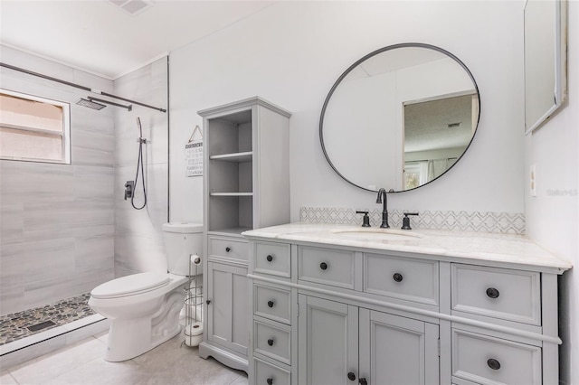 bathroom featuring toilet, decorative backsplash, tiled shower, and vanity