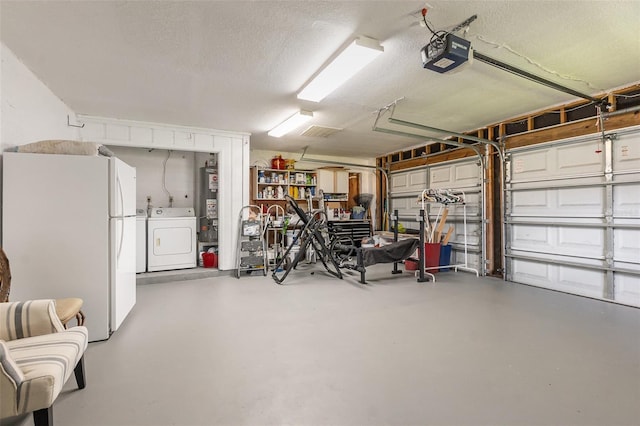 garage featuring washing machine and clothes dryer, freestanding refrigerator, and a garage door opener