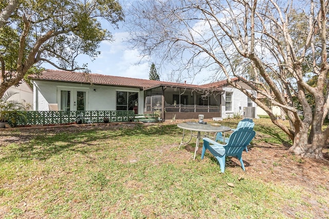 rear view of house featuring central AC unit, a sunroom, a tile roof, french doors, and stucco siding