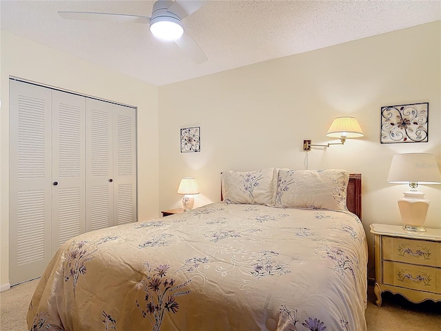 bedroom with a textured ceiling, a closet, a ceiling fan, and light colored carpet