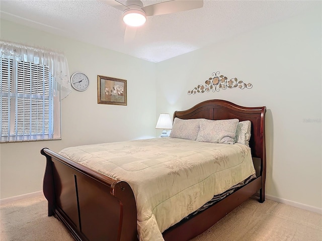 bedroom with a ceiling fan, light colored carpet, a textured ceiling, and baseboards