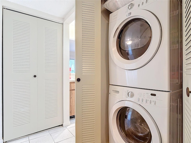 laundry area with laundry area, stacked washing maching and dryer, and light tile patterned floors