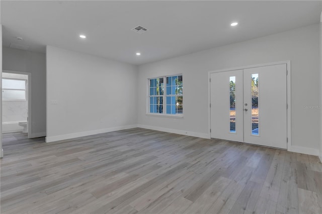 foyer entrance with plenty of natural light, light wood-type flooring, and french doors