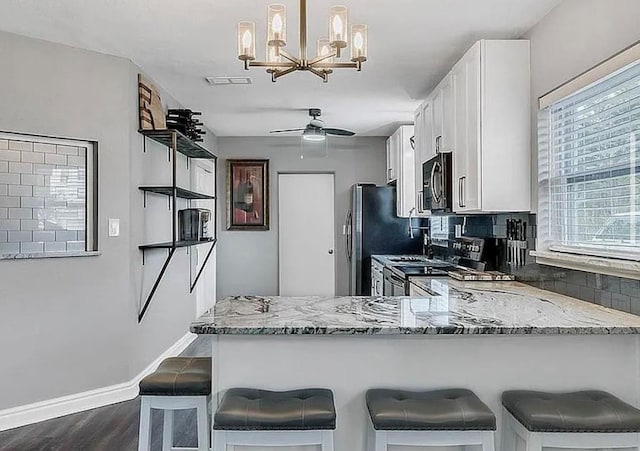 kitchen featuring a peninsula, stove, white cabinetry, a kitchen breakfast bar, and hanging light fixtures