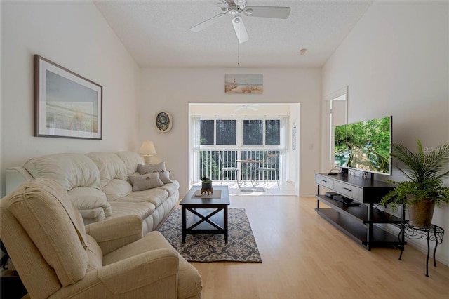 living room with a textured ceiling, light wood-style flooring, and a ceiling fan